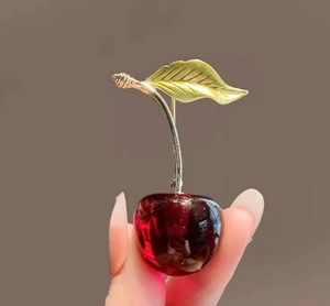 Detailed view of luxury red cherry brooch with gold leaves and translucent resin beads
