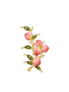 Macro detail of peach brooch with pink enamel fruits and green leaves on gold branch