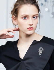 Elegante Blumenbrosche mit weißer Perle und Kristallen an einem schwarzen Kleid am Model