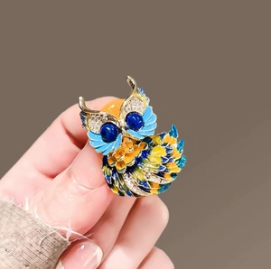 Exquise broche hibou en émail bleu et jaune avec strass étincelants sur métal doré