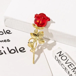 Broche rose en émail rouge avec tige dorée sur un support de présentation blanc élégant