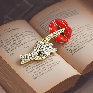 Elegant red enamel lips and gold pave crystal hand brooch set on a vintage book