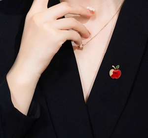Detail of a red apple brooch with crystal inlay on a black blazer lapel for women