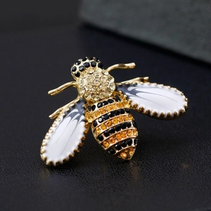 Macro shot of bee brooch with yellow rhinestones and black enamel wings on dark leather