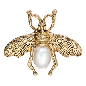 Détail d'une broche abeille dorée vintage avec ailes ciselées et incrustation de perle