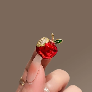 Detailed macro view of a red apple brooch with gold plating and white zircon inlay
