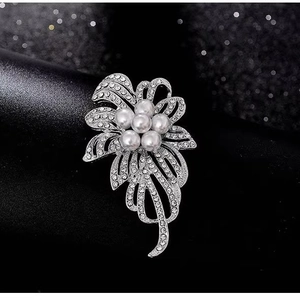 Broche fleur scintillante avec strass blancs et perles sur fond noir élégant