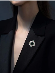 Close-up of elegant emerald crystal brooch pinned on a black suit lapel for women