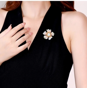 Dettaglio di un'elegante spilla a fiore di peonia con perle su un abito nero classico