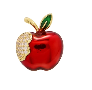 Macro detail of red enamel apple brooch with sparkling crystals and golden metal finish