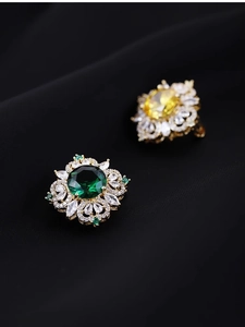 Detail of luxury emerald and yellow crystal brooches with marquise cut stones on black fabric