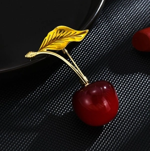 Elegant cherry brooch with red glossy fruit and golden leaves on black background