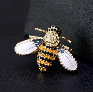 Spilla a forma di ape dorata con strass gialli e neri su sfondo di pelle nera pregiata