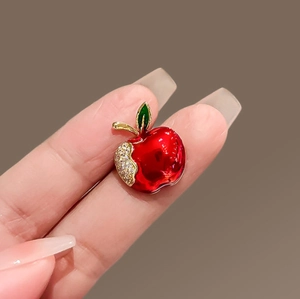 Elegant red apple brooch with gold plating and crystals on a dark background