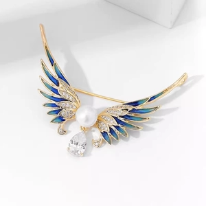 Détail de broche ailes d'ange avec émail bleu, perle blanche et zircone en goutte