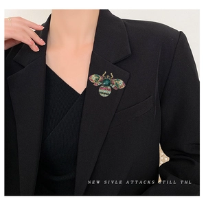 Vintage gold crystal bee brooch with multi-colored gemstones on a black suit jacket