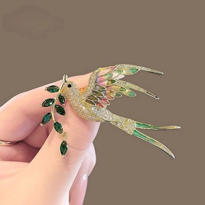 Détail de la broche pie en or avec zircons blancs et finition émaillée dégradée
