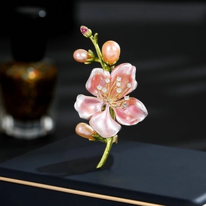Dettaglio di spilla a fiore di magnolia con petali in smalto rosa e accenti di perle