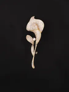 Dettaglio ravvicinato della spilla a forma di calla con finitura dorata e cristalli