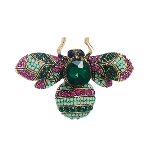 Detailed view of vintage bee brooch with colorful crystals and faceted green gemstone