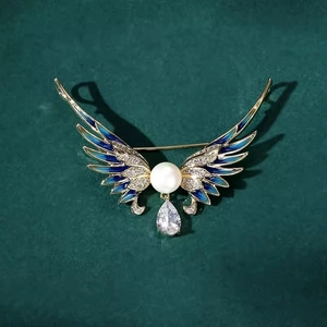 Détail d'une broche ailes d'ange en émail avec perle blanche et zircon suspendu