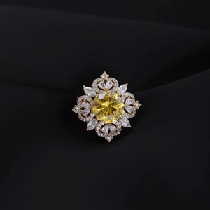 Elegant floral brooch with a yellow gemstone and white crystals on black silk fabric