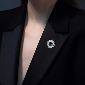 Elegant emerald crystal brooch with starburst pattern on a dark suit lapel
