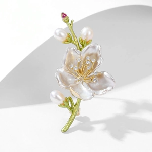 Dettaglio della spilla a magnolia in smalto con zirconi incastonati e eleganti perle bianche