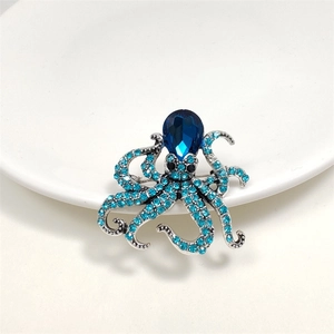 Macro detail of octopus brooch with sky blue crystals and pear-shaped sapphire gem
