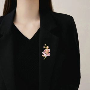 Dettaglio della spilla a fiore di magnolia rosa con perle su una giacca nera
