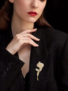 Dettaglio della spilla a tulipano dorata con cristalli scintillanti su blazer nero in tweed