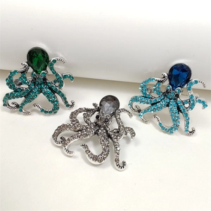 Detailed macro view of three octopus brooches with emerald, gray, and blue crystals