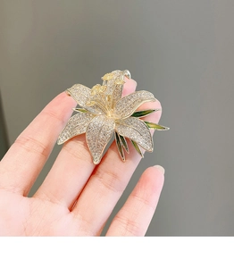Macro shot of luxury lily brooch with pavé rhinestones and yellow crystal center