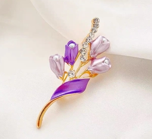 Makroaufnahme einer Tulpenbrosche mit lila Emaille und weißen Perlen auf Seide