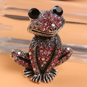 Macro shot of vintage silver frog brooch featuring sparkling red and AB colored rhinestones