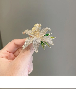 Detailed close-up of luxury lily brooch with white zircons and green enamel leaf