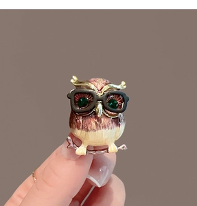 Vue détaillée de la broche hibou en émail avec pierres vertes et lunettes rondes