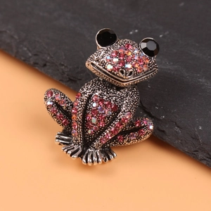Macro detail of frog brooch with pink crystals and vintage silver metal texture