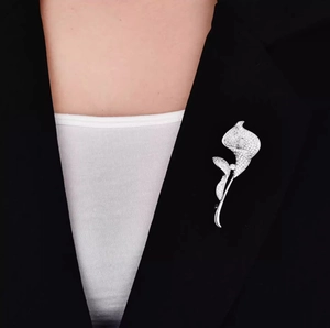 Dettaglio di una spilla a forma di calla in argento con cristalli bianchi su un blazer nero