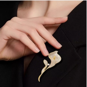 Dettaglio della spilla calla dorata con cristalli scintillanti su una giacca blazer nera