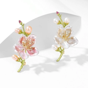 Dettaglio della spilla magnolia con petali in smalto rosa e perle su sfondo bianco
