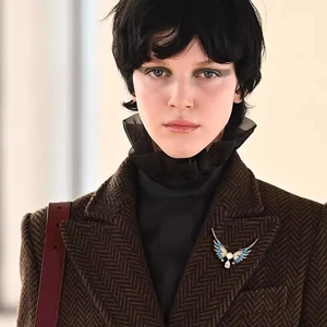 Détail d'une broche ailes d'ange en émail bleu portée sur le revers d'un manteau