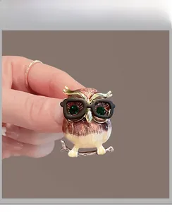 Détail de la broche hibou avec émail rose, yeux en gemme verte et lunettes noires