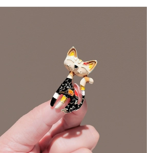 Close-up of a vintage black cat brooch with enamel details held by fingers