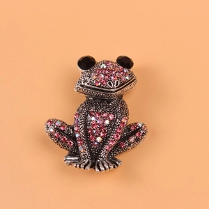Macro detail of retro frog brooch featuring pink rhinestones and antique silver finish