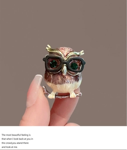 Détail de la broche hibou avec yeux en gemme verte et finition en émail marron