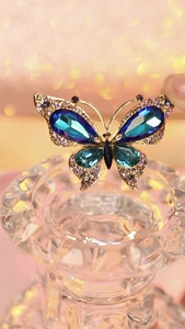 Macro view of crystal butterfly brooch with peacock blue gems and golden metal framing