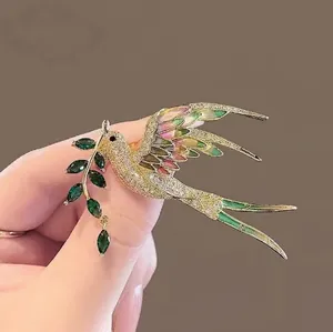 Élégante broche oiseau pie dorée avec ailes colorées et charme branche d'olivier zircon