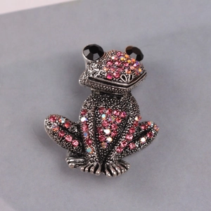 Close-up of vintage frog brooch featuring pink rhinestones and black gem eyes