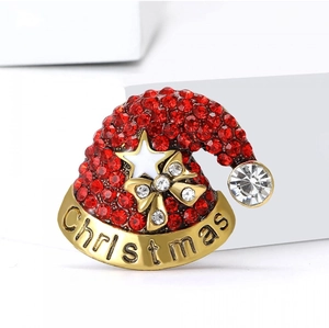 Détail de la broche bonnet de Noël en strass rouges brillants avec texte doré Christmas